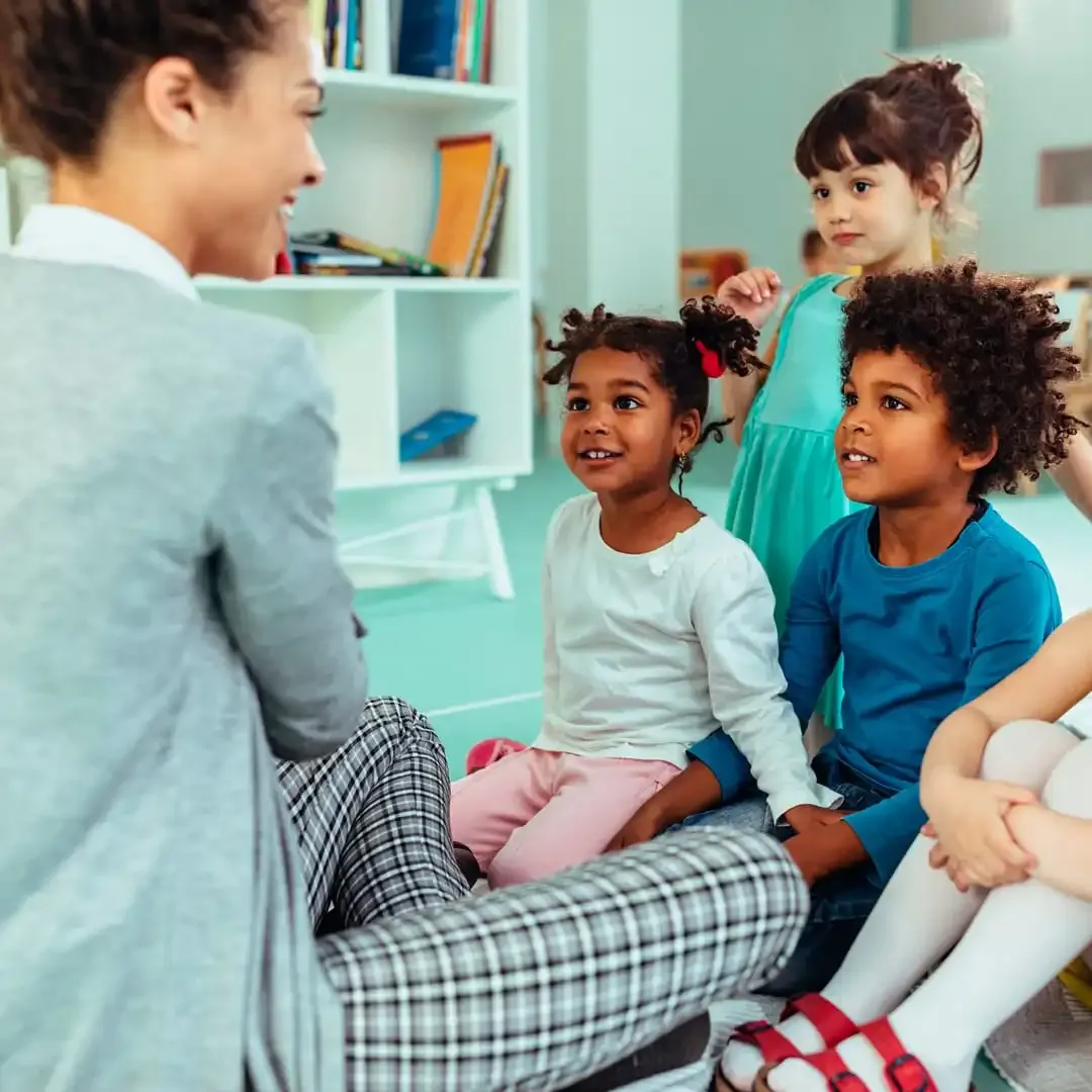 Caregiver talking with children sitting in a circle