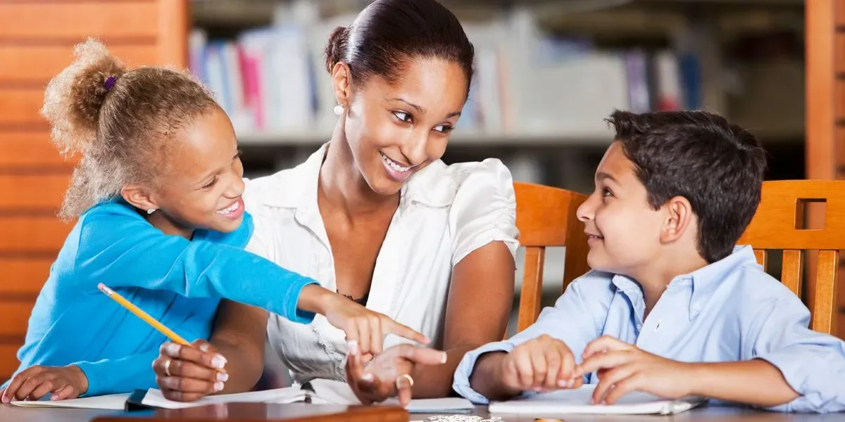 Caregiver helping two children with their schoolwork