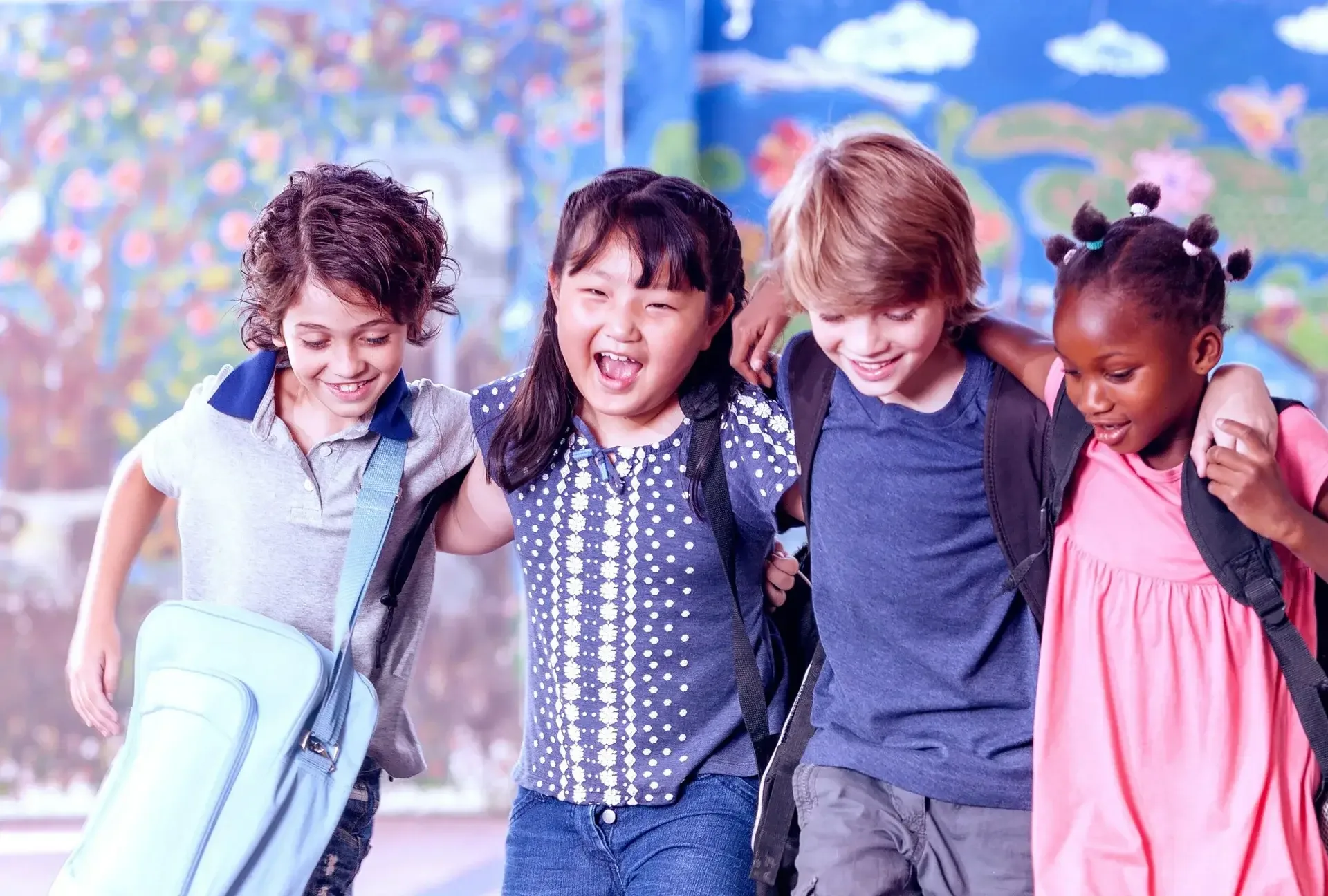 Four children walking arm in arm with backpacks