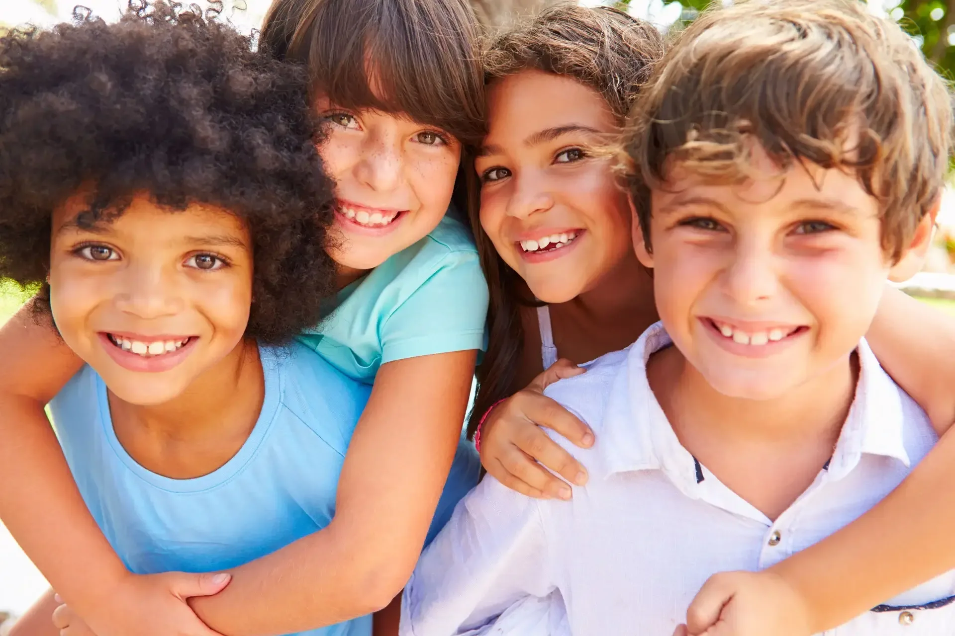 Four smiling children hugging each other