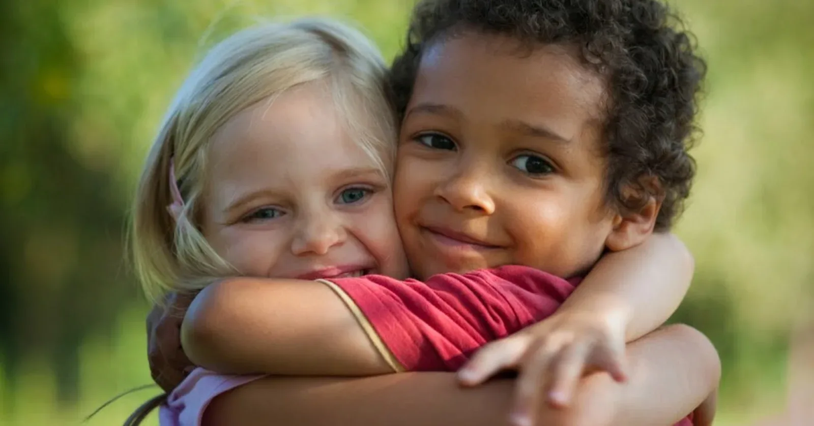 Two young children hugging outdoors