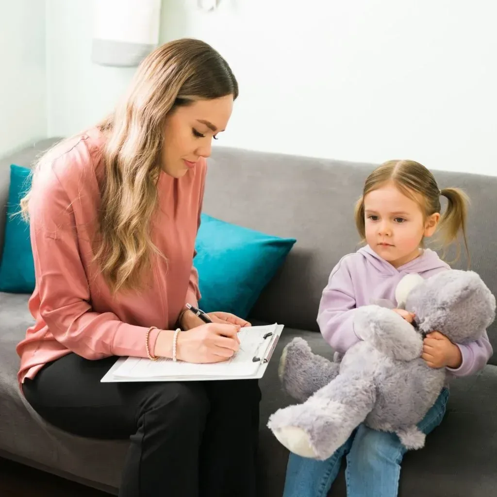 Caregiver taking notes while talking with a young girl