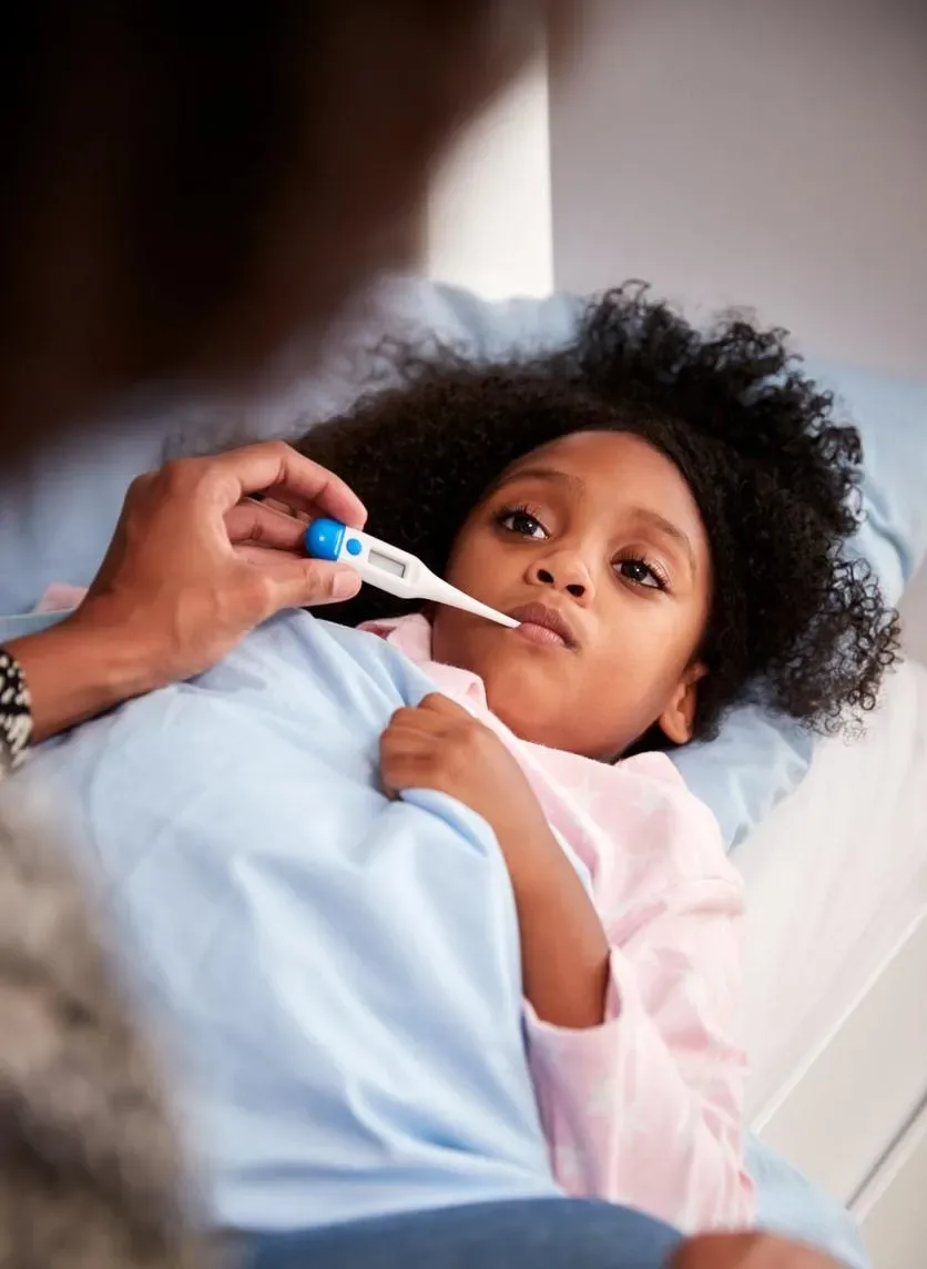 Parent checking a resting child's temperature with a thermometer
