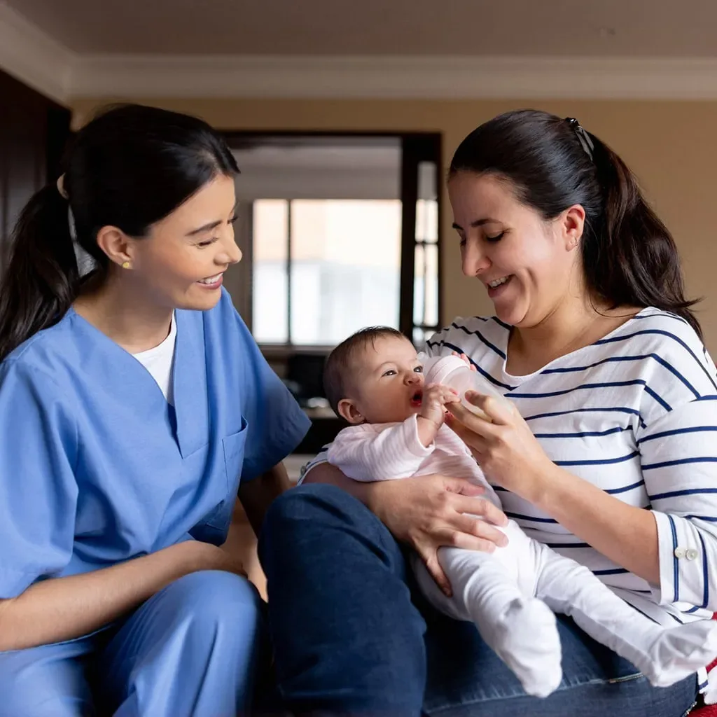 Home care nurse sitting with a mother holding her baby