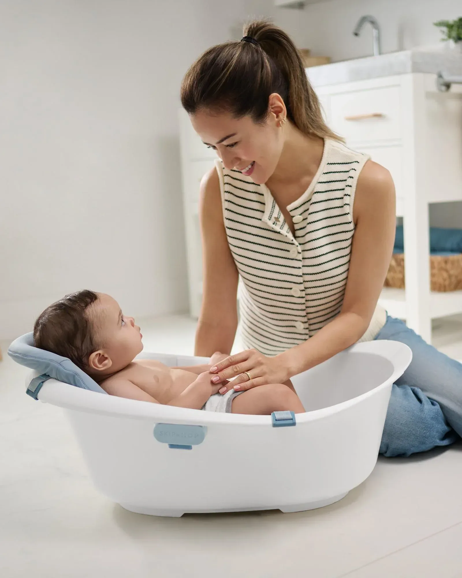 Mother bathing her baby in an infant tub at home