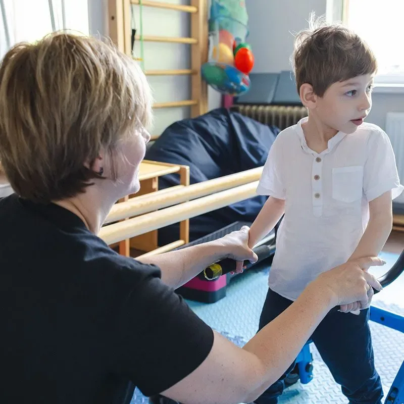 Therapist helping a young boy practice walking