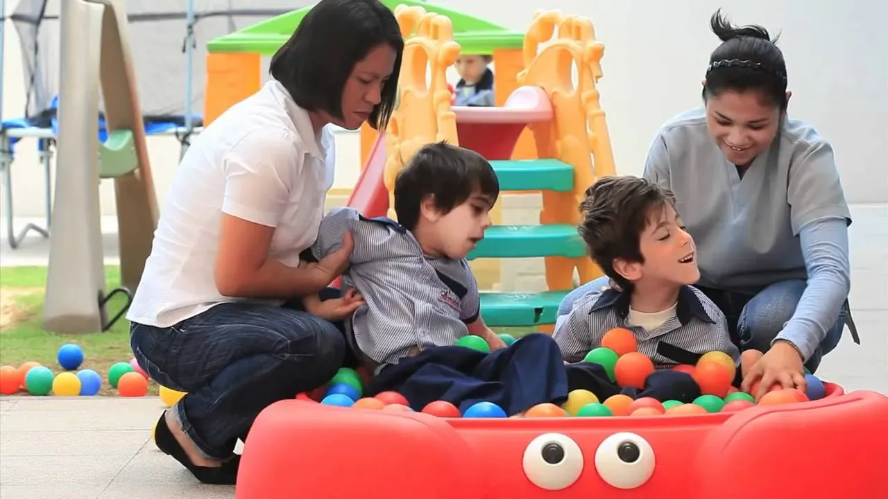 Therapists playing with two children at a ball pit
