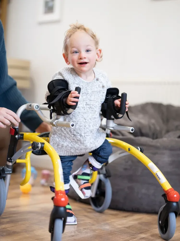 Toddler walking with a gait trainer at home
