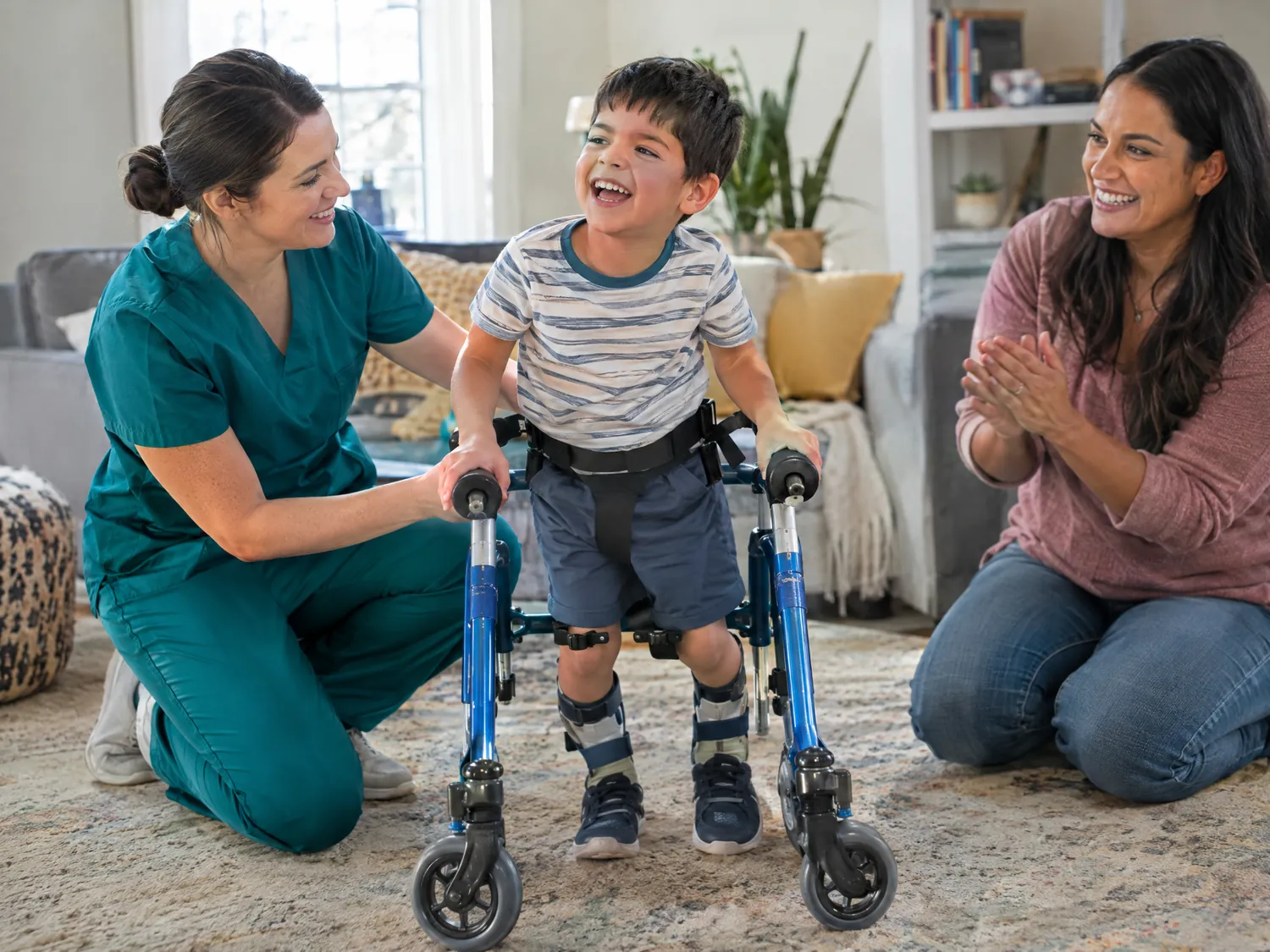 Caregiver supporting a boy practicing with a walker as his mother cheers