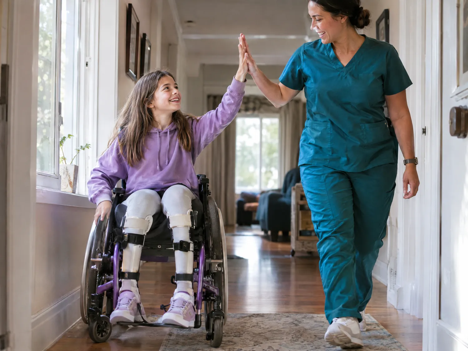 Girl with leg braces in a wheelchair high-fiving her caregiver